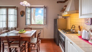 A kitchen with a gas stove, a refrigerator, and a window with a view of the countryside. - Apartment Giotto by Interhome (Montaione)