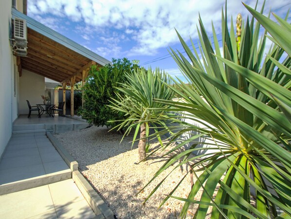 A covered patio area with outdoor seating and a variety of plants.