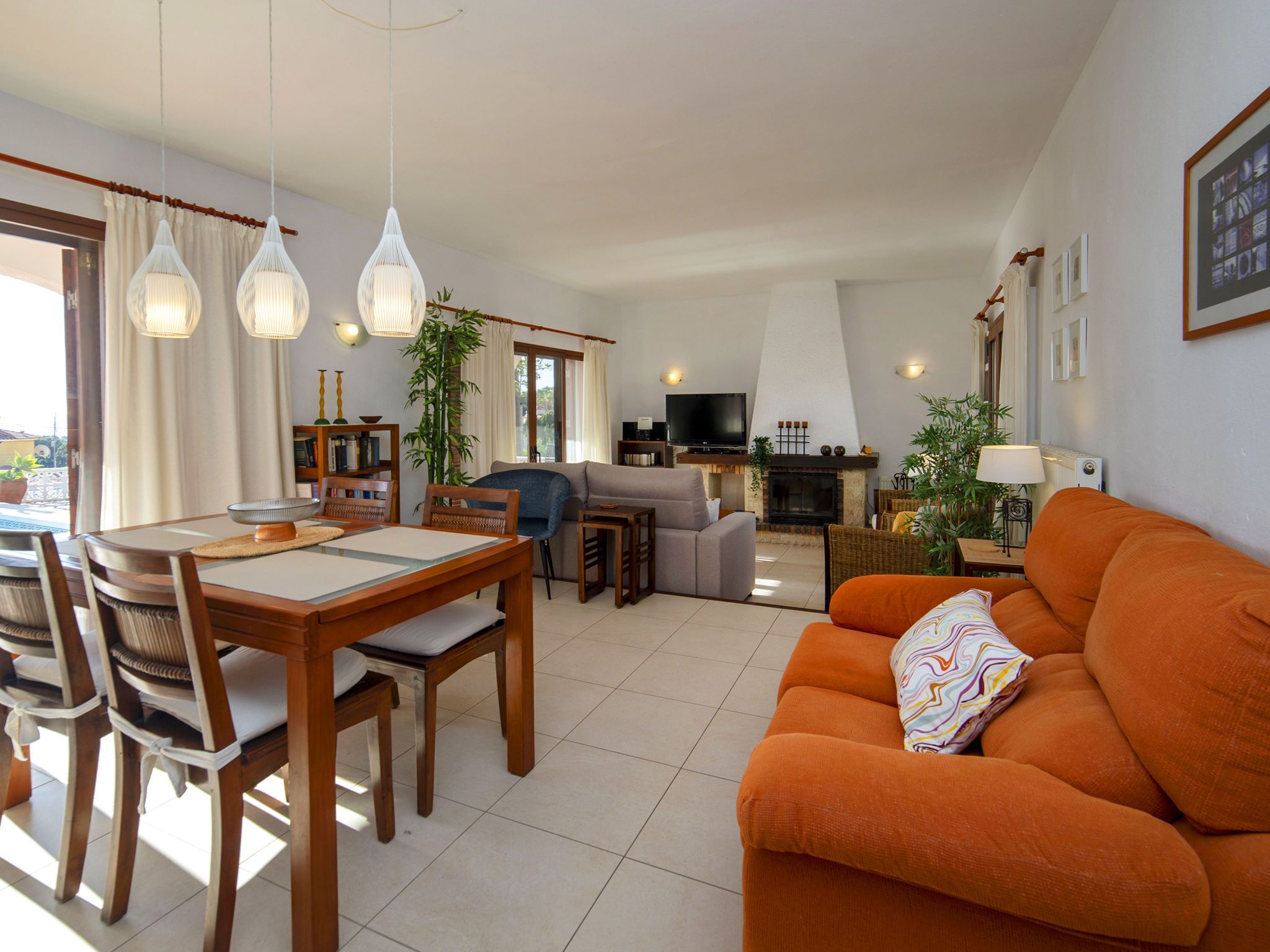 Ein modernes Wohnzimmer mit Essbereich, einer Couch, einem Fernseher und einem Kamin.