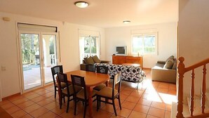 A spacious living area with a dining table, chairs, a sofa, and a TV. - Villa Alguer by Interhome (L'Ametlla de Mar)