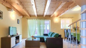 Un salon avec un canapé, une table basse, un téléviseur posé sur un meuble et un escalier.