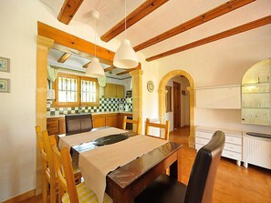 Una cocina acogedora con vigas de madera, una mesa de comedor con sillas y una encimera con fregadero y armarios.