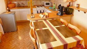 Une cuisine compacte comprenant une table en bois, des chaises, un réfrigérateur, un four à micro-ondes et une machine à café.