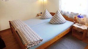 Une petite pièce agréable, avec un lit, une table de chevet, une lampe et une fenêtre avec des rideaux.