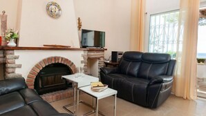 A living room with a fireplace, leather sofa, and a television on a stand. - Torre Mar by Interhome (Miami Platja)