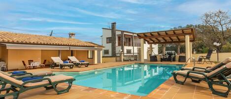 A pool area with lounge chairs and a pergola.