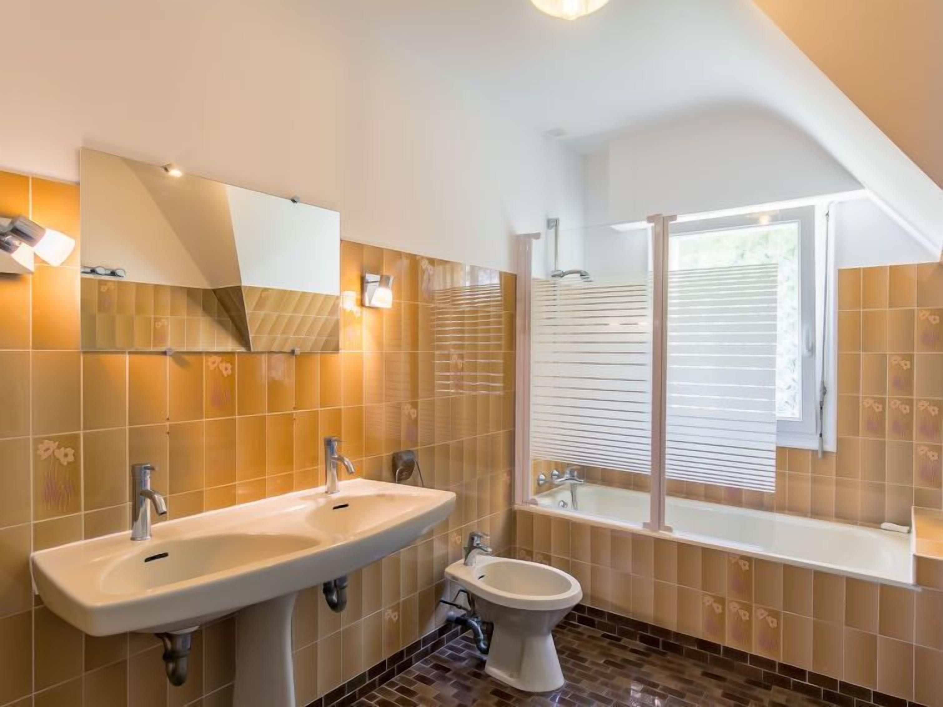 A modern bathroom with a sink, bidet, and bathtub.