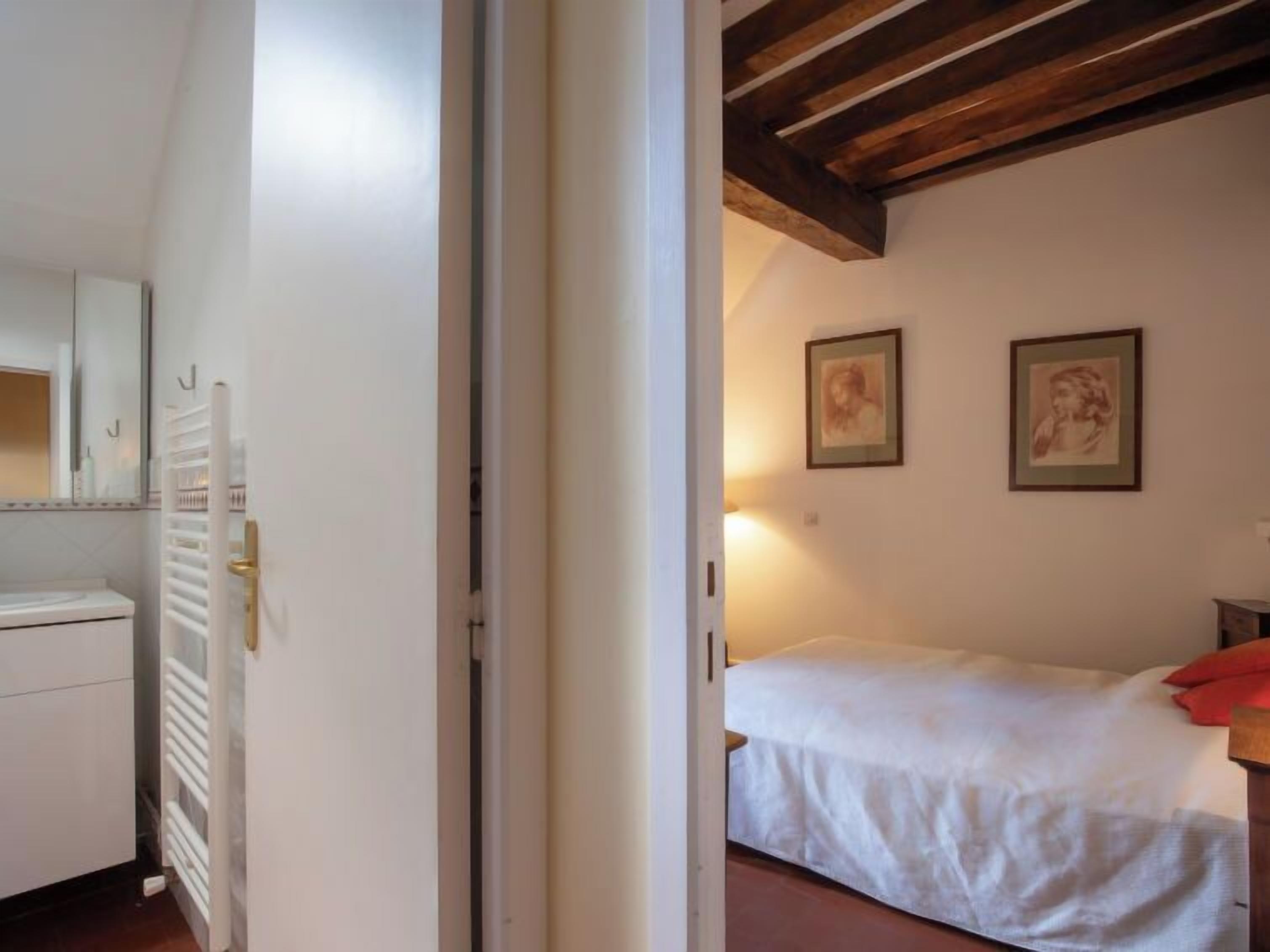 A bedroom with a bed, a nightstand, and two framed pictures on the wall.
