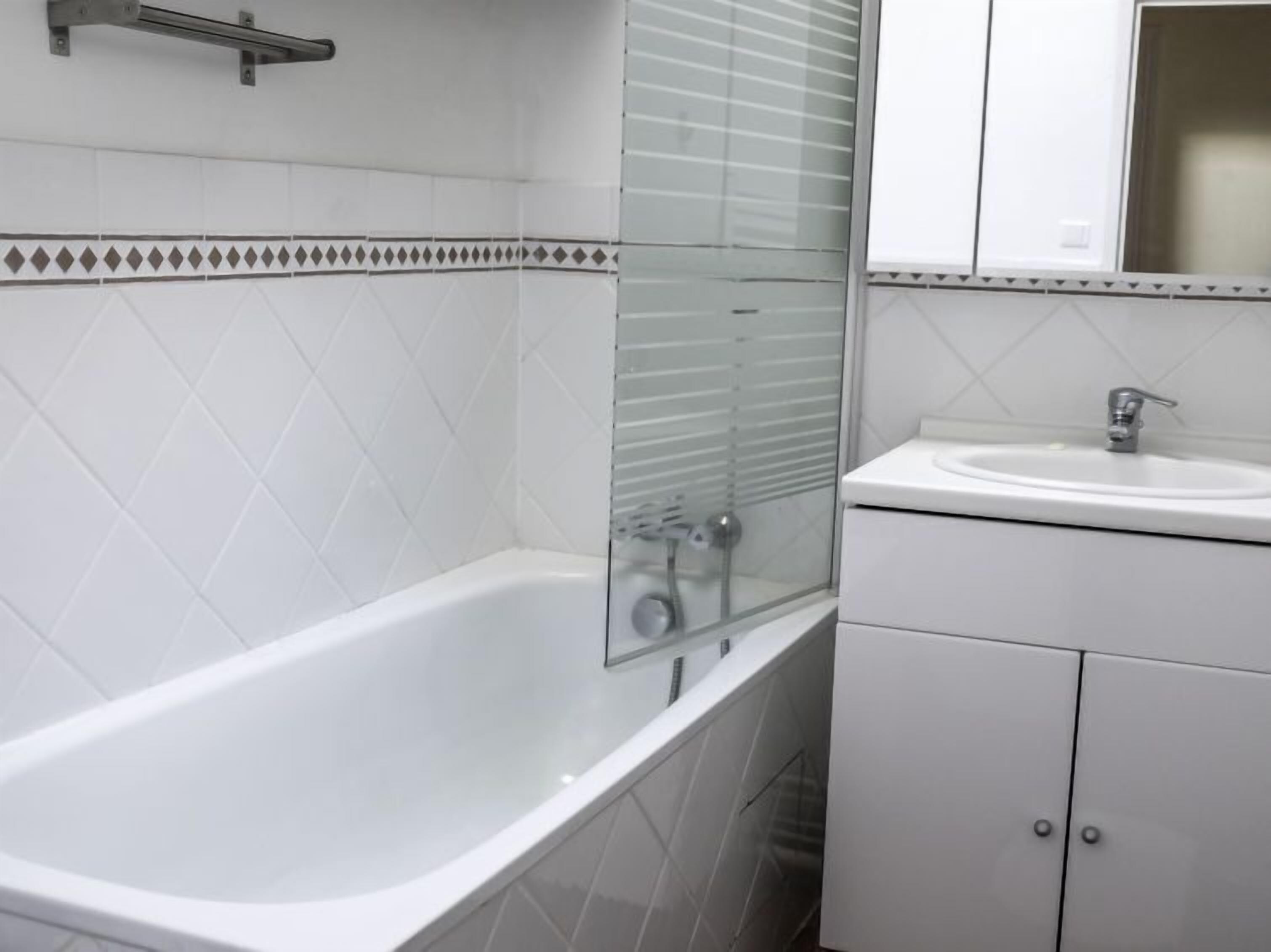 Ein Badezimmer mit einer weißen Badewanne, einer Duschkabine aus Glas und einem weißen Waschbecken mit Spiegel darüber.