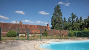 En swimmingpool med en mur av tegelsten och ett grönt staket i bakgrunden.