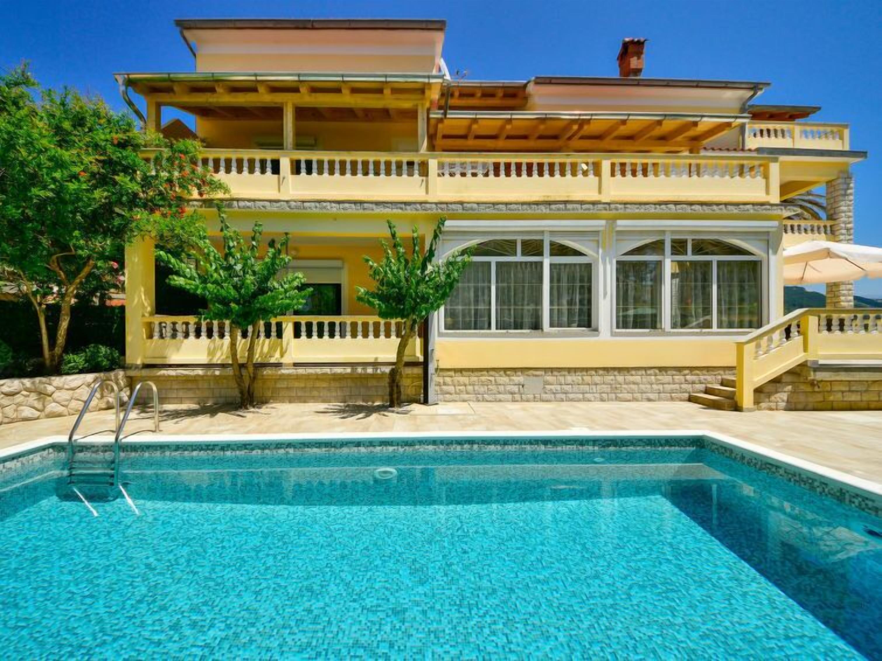 A two-story house with a swimming pool in front.
