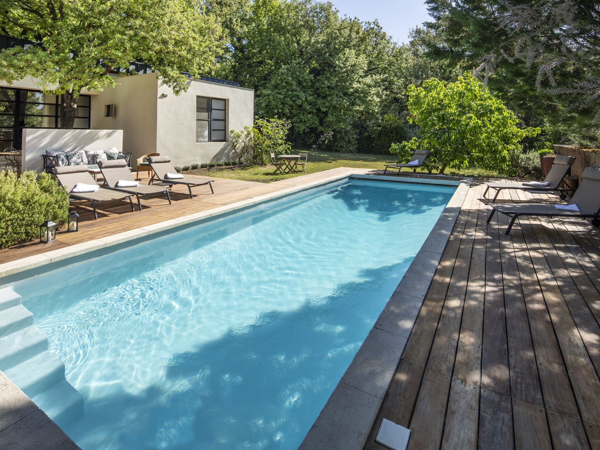 A rectangular swimming pool with a wooden deck surrounding it.