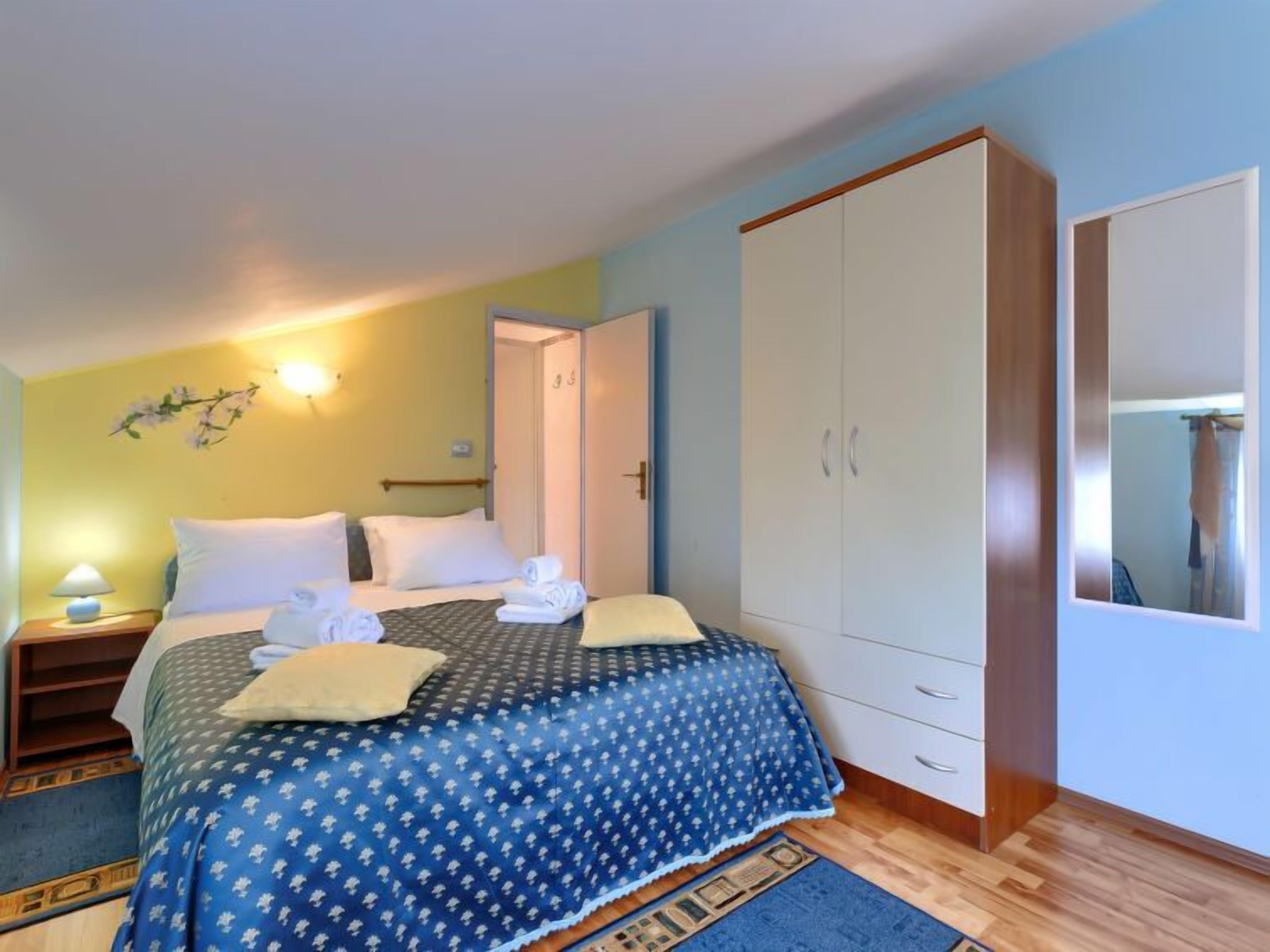 Een slaapkamer met een bed, nachtkastjes, een kledingkast en een spiegel.