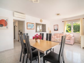 Una sala de estar moderna con un sofá, una mesa de comedor con sillas, un televisor y obras de arte en las paredes.
