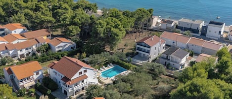 Ett bostadsområde vid kusten med hus, en swimmingpool och en strand.