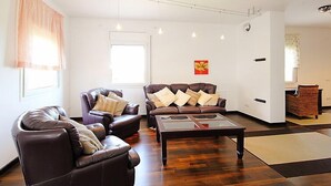 A spacious living room with leather sofas, a glass coffee table, and a large window providing natural light. - Vacation home Dirk by Interhome (L'Ampolla)