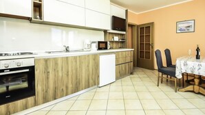A compact kitchen with white cabinets, a microwave, and a built-in oven. There is a dining area with a table and chairs, and a door leading to another room.