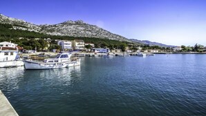 A marina with boats docked, a mountainous backdrop, and buildings along the waterfront.