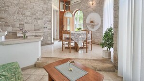 Un comedor con pared de piedra, una mesa de madera con posavasos y una planta en maceta.