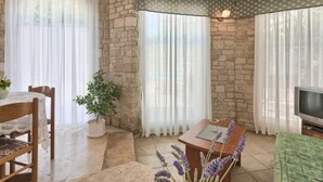 Una sala de estar acogedora con pared de piedra, una mesa de madera, un televisor y una planta en maceta.