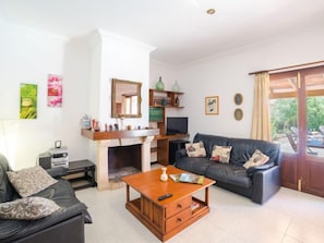 Uma sala de estar com lareira, sofá, mesa de centro e televisão.