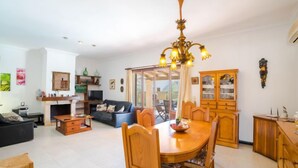 A spacious living room with a dining area, a fireplace, and a large window. - Vacation home Sanso by Interhome (Porto Cristo)