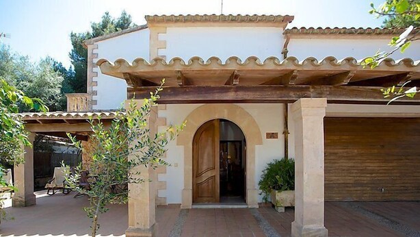 A building with a covered entrance, a garage, and a patio area with outdoor furniture. - Vacation home Sanso by Interhome (Porto Cristo)