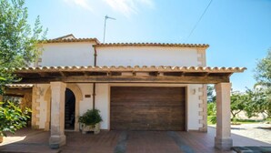 A two-story house with a tiled roof, a garage, and a covered entrance with columns. - Vacation home Sanso by Interhome (Porto Cristo)