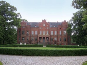 A large, red brick building with a symmetrical facade, multiple windows, and a central clock tower.