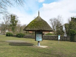 Een paviljoen met rieten dak en een bord in een park.