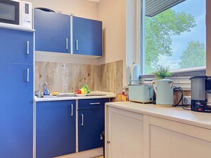 Cocina compacta con armarios azules, microondas, tostadora y cafetera.