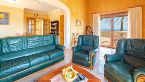 A living room with a green sofa, two leather armchairs, and a coffee table. There is a bookshelf and a door leading to another room. - Cala Torta Na Lluny by Interhome (Cala Torta)