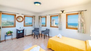 A hotel room with two beds, a small desk, a mirror, and a view of the sea. - Cala Torta Na Lluny by Interhome (Cala Torta)