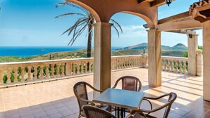 A covered outdoor seating area with a view of the sea and hills. - Cala Torta Na Lluny by Interhome (Cala Torta)