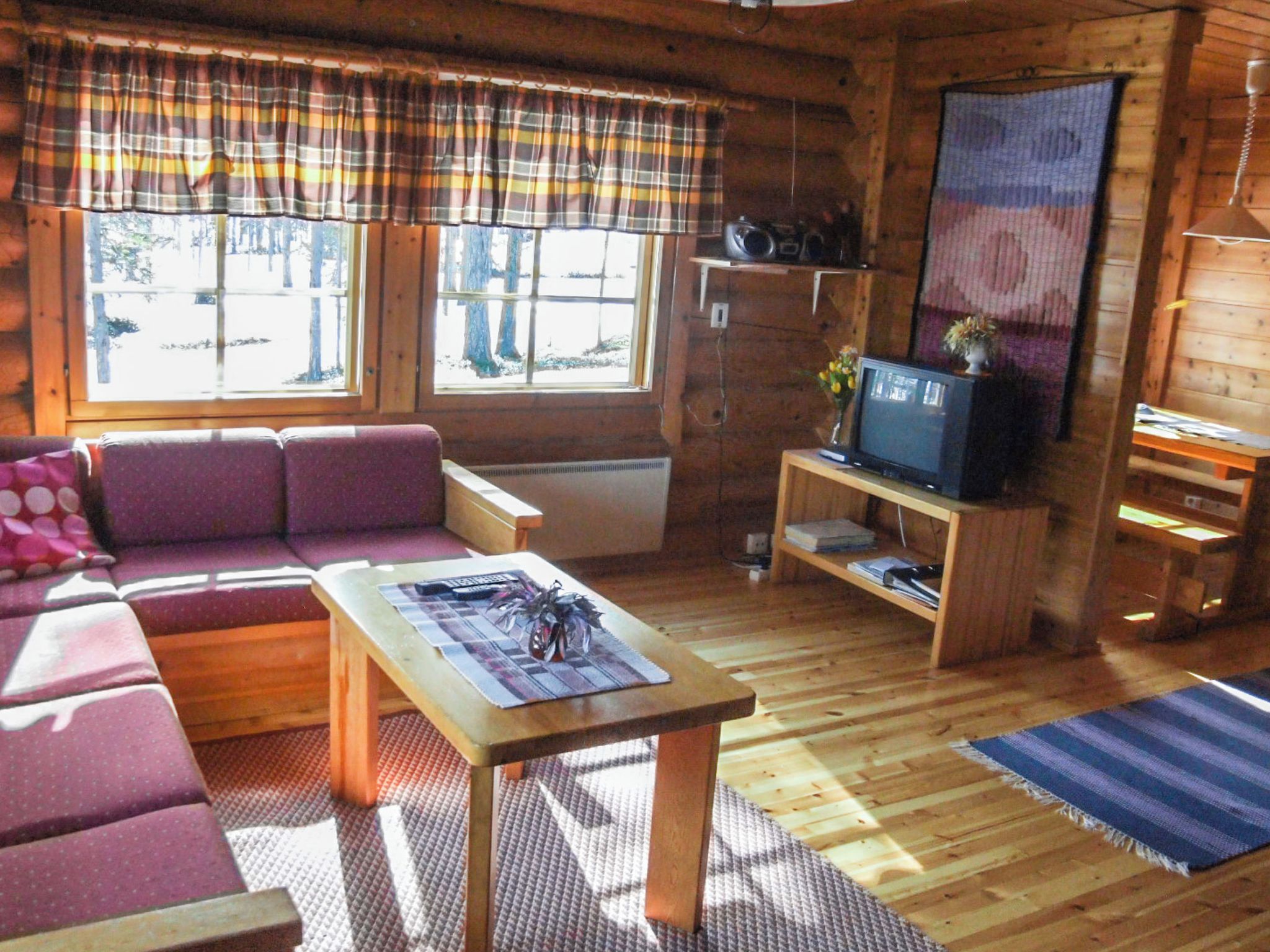 A cozy cabin interior with a sofa, a television, and a small table.