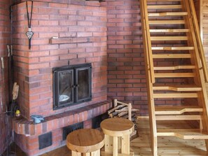 A brick fireplace with a wooden ladder, two stools, and a hanging ornament. - Kujalan lomat 2 by Interhome (Kuusamo)
