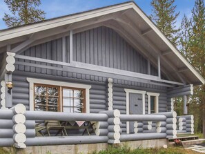 Eine Blockhütte mit Satteldach, großen Fenstern und einer Veranda mit Geländer.