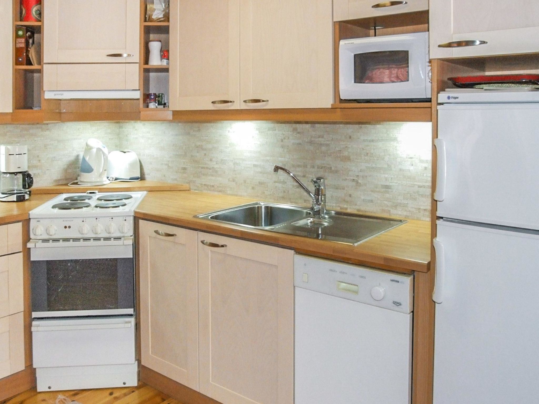 Una cocina compacta equipada con estufa, lavamanos, microondas y refrigerador.