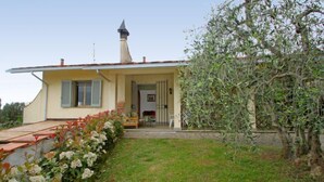 A two-story house with a small porch, a chimney, and a garden with flowering plants. - Magnolia by Interhome (Montaione)
