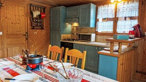 Una cocina acogedora con armarios de madera, microondas y una mesa de comedor preparada para cuatro personas.