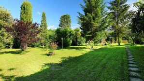 Un jardín bien cuidado con varios árboles, césped y un sendero de piedra.