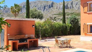 Ein Poolbereich mit Grill, Sitzgelegenheit im Freien und einem Bergpanorama.
