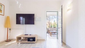 Una sala de estar moderna con un televisor de pantalla plana, un mueble de madera para entretenimiento, un sofá y una lámpara.