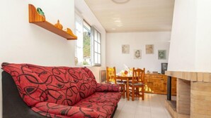 Un salon comprenant un canapé, une table à manger avec des chaises, une cheminée et un coin cuisine.