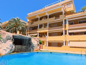 Et hotel med pool, klippeformation og altaner.