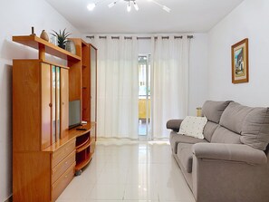 Una sala de estar con mueble de entretenimiento de madera, un sofá gris y un cuadro en la pared.