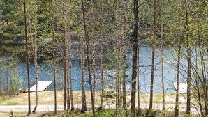 Une zone boisée avec une tente et un bâtiment en arrière-plan.