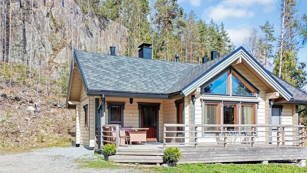 Une cabane dotée d’une véranda, d’un coin repas et d’une grande fenêtre.