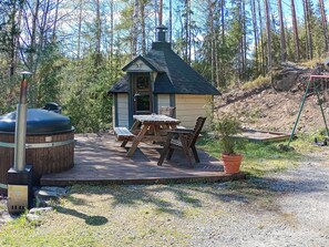 A wooden deck with picnic tables and a hot tub.