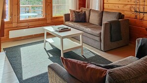 L’intérieur d’un chalet accueillant, avec un canapé, une petite table et une chaise.